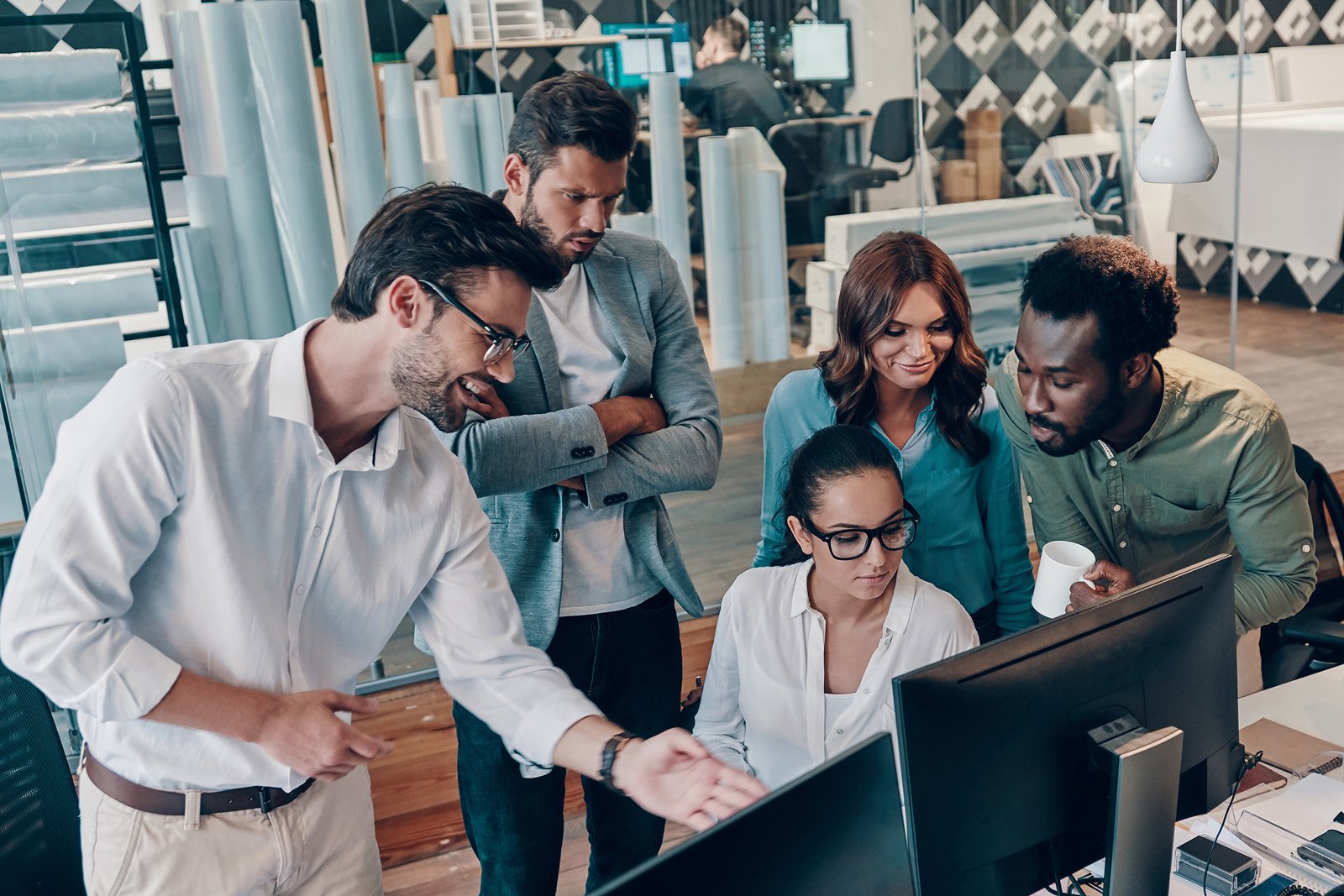 Group of young modern people in smart casual wear discussing business while working in the office